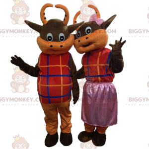 2 brown and orange cows dressed in colorful outfits –
