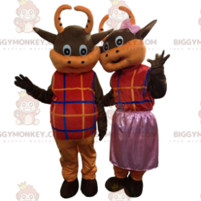 2 brown and orange cows dressed in colorful outfits –